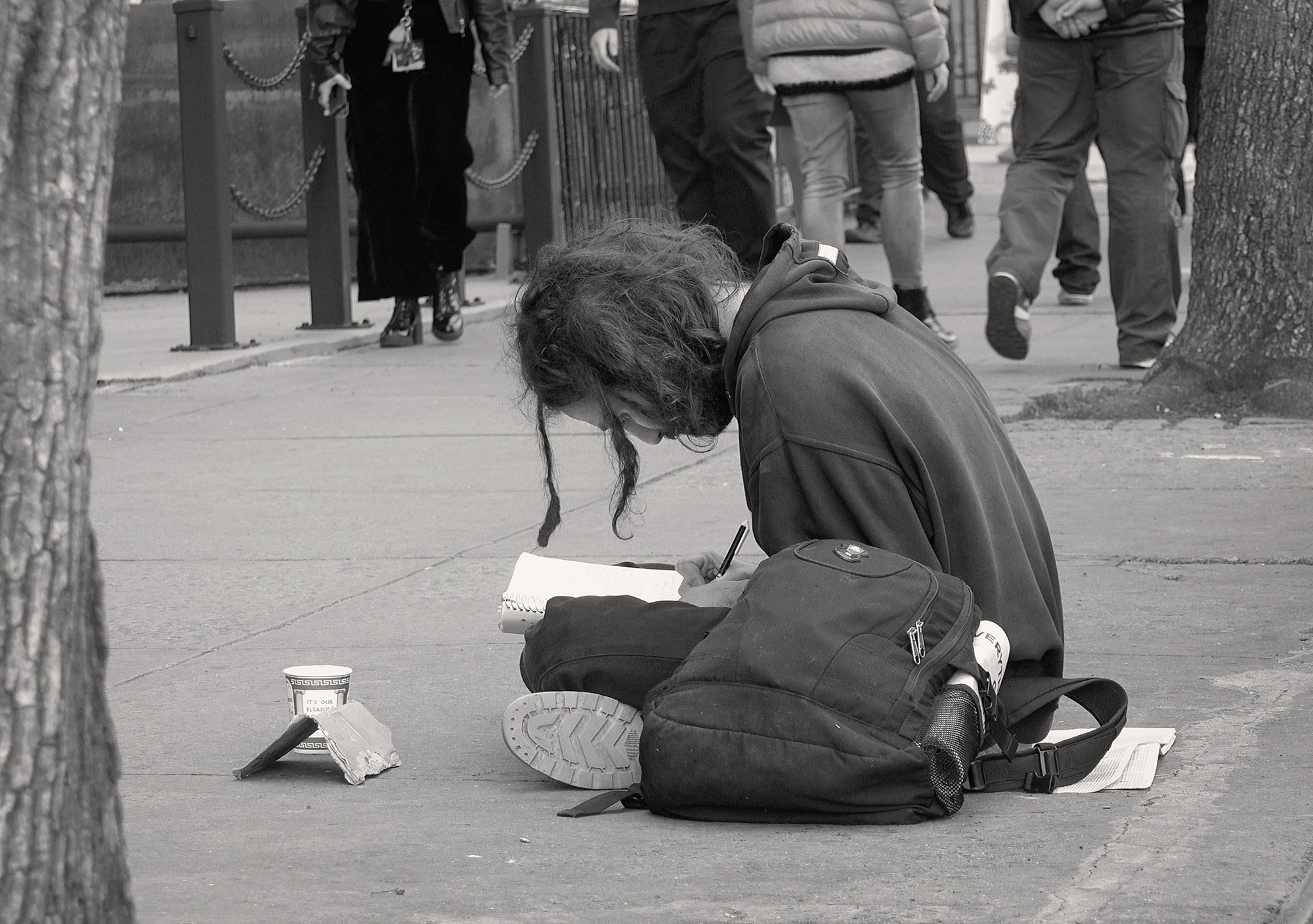Christoph Radke, New York City, youn man squatting on a sidewalk, reading a book, 2016